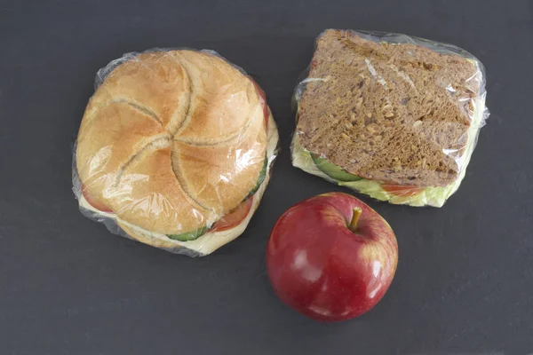 Sanduíches embalados com filme stretch e maçã vermelha — Fotografia de Stock