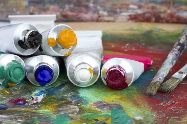 Paint colors and brushes on artist palette — Stock Photo, Image