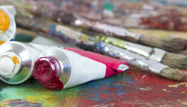 Paint colors and brushes on artist palette — Stock Photo, Image