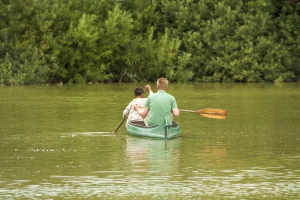 Family on canoe tour. Father and child paddling in kayak in a lake