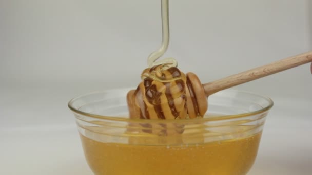 Honey in glass bowl and wooden dipper — Stock Video