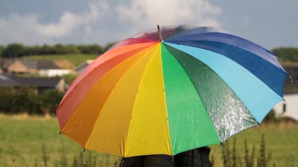 Une personne avec un parapluie de couleur arc-en-ciel sous la pluie 