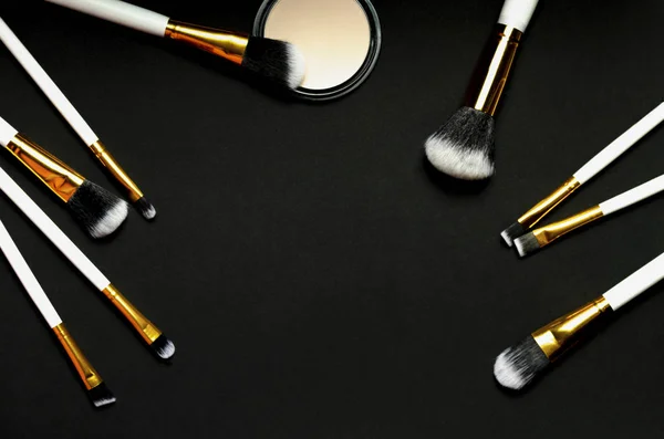 Clouse-up of makeup brush and face powder on black background.Top view.