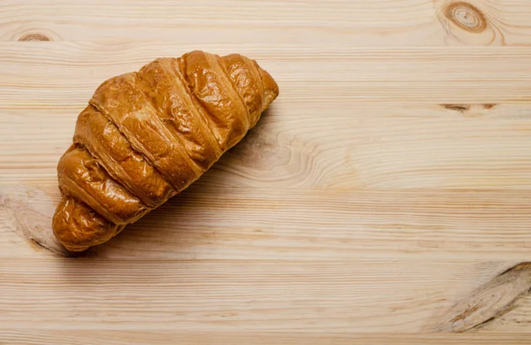 Freshly baked croissant on wooden table. — Stock Photo, Image