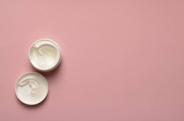 Bankanın beyaz kremi var, kapağı açık, pembe arka plan, kozmetoloji, güzellik derisi.