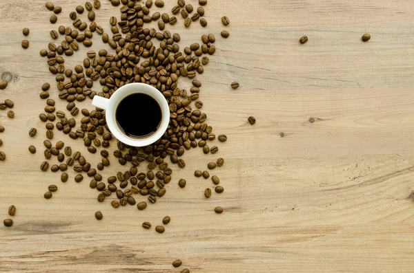 ?up of hot coffee, scattered coffee beans on a wooden light background. Romantic evening, breakfast, dinner. View from above.Place for text. Blurred background