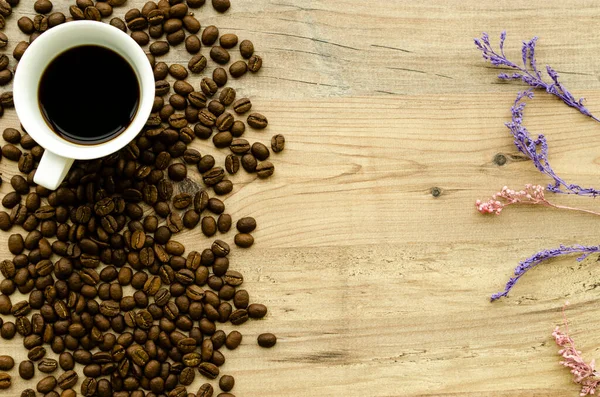 ?up of hot coffee, scattered coffee beans, heather on a wooden light background. Romantic evening, breakfast, dinner. View from above