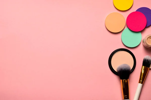 Makeup brush, sponges and face powder on pink background.Makeup products to even out skin tone and complexion.Top view.Top view