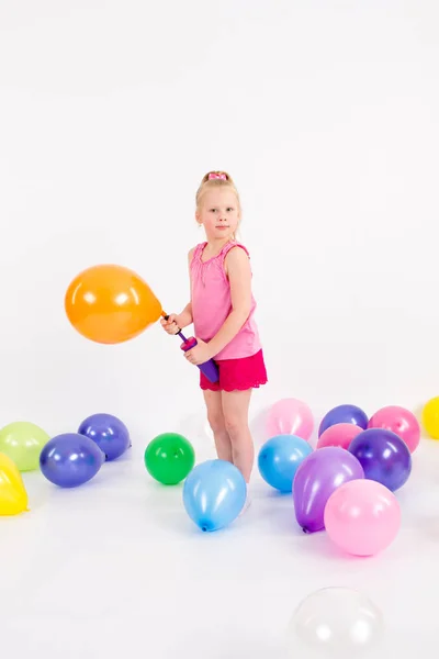 Malá holčička nafoukne balónek na bílém pozadí — Stock fotografie