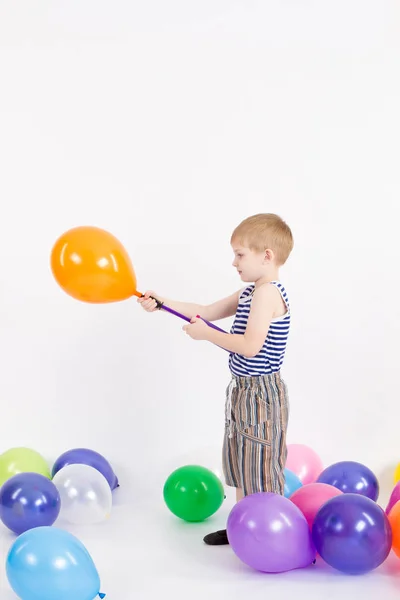Het jongetje wordt opgeblazen ballon op de witte achtergrond van de — Stockfoto