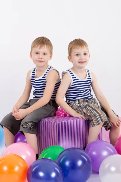 Twee jongens zitten met een gift op een witte achtergrond, de inscriptie gelukkige verjaardag — Stockfoto
