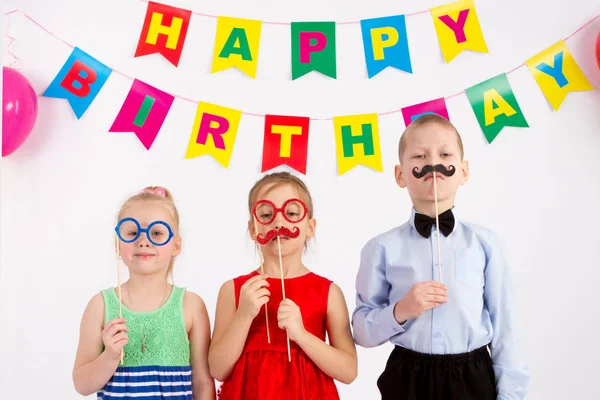 Діти тримають карнавальні вуса та окуляри, напис з днем народження, білий фон — стокове фото