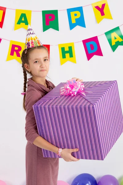 Mädchen hält eine große Schachtel mit einem Geschenk. Girlande mit der Aufschrift Happy Birthday. weißer Hintergrund. — Stockfoto