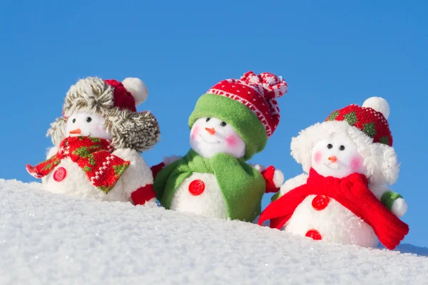 The winter, Christmas - three happy snowmen stand against the background of the blue sky. — Stock Photo, Image