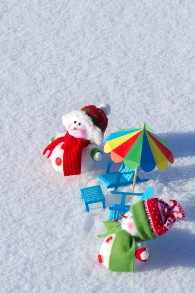 Two cute snowman sunbathing in the snow. Paper beach chairs and a  umbrella. Winter background — Stock Photo, Image