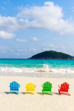 Plaj sandalyeleri oturup sahilde kırma yumuşak okyanus dalgalarının rahatlayın turistler için kumlu plajları üzerinde. Kağıttan yapılmış.