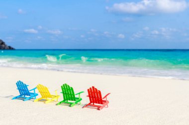 Plaj sandalyeleri oturup sahilde kırma yumuşak okyanus dalgalarının rahatlayın turistler için kumlu plajları üzerinde. Kağıttan yapılmış.