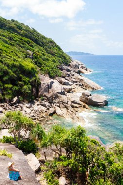 Mavi elbiseli kız taş üzerine oturan ve ufuk mesafe içine arıyorum