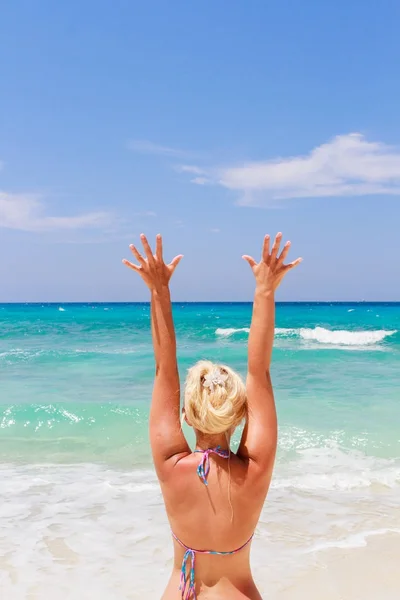 Ragazza con le braccia alzate che guarda un mare color smeraldo. La vista dal retro . — Foto Stock