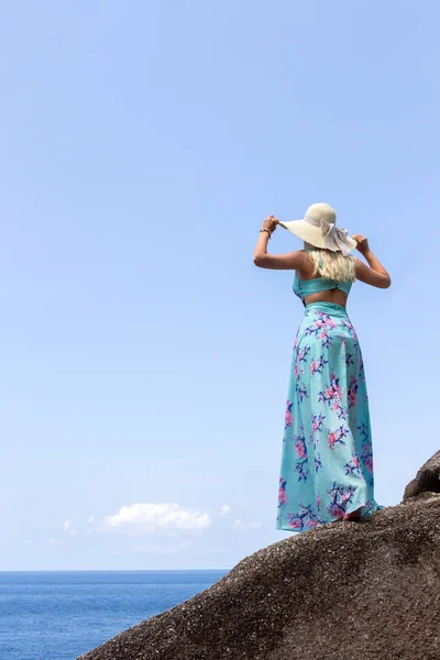 Chica en un vestido azul de pie sobre piedra y mirando a la distancia del horizonte — Foto de Stock