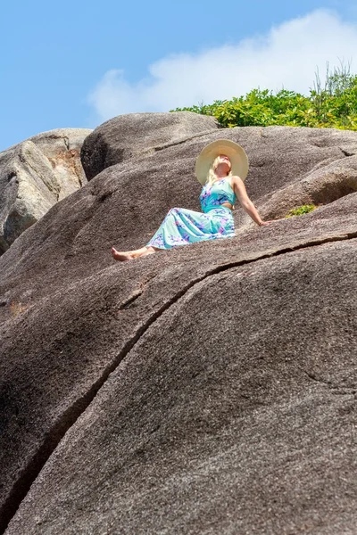 Chica en un vestido azul está sentado en piedra y mirando a la distancia del horizonte — Foto de Stock