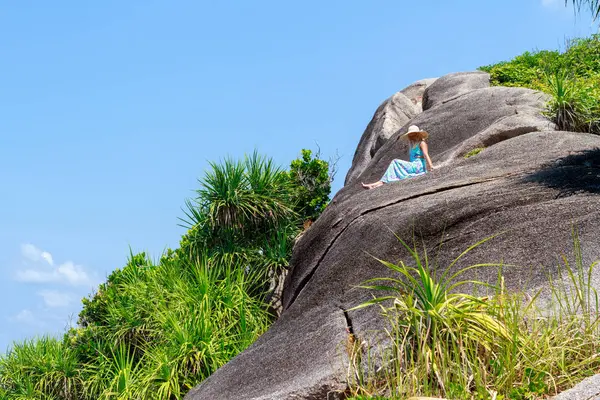 Mavi elbiseli kız taş üzerine oturan ve ufuk mesafe içine arıyorum