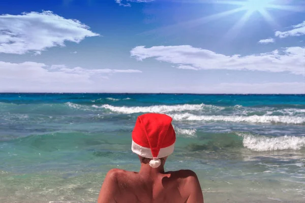 Papai Noel com tampa vermelha olhando para a distância do oceano infinito. Céu azul . — Fotografia de Stock