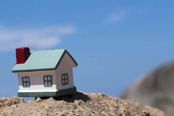 Toy houses standing on rock on background of the sky — Stock Photo, Image