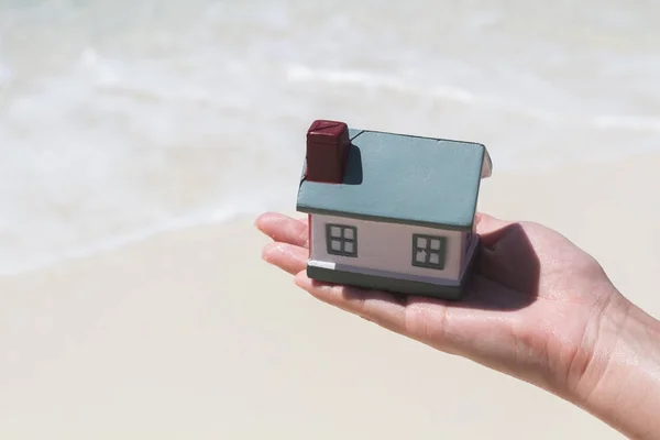 Toy houses keeps on hand against the blue sea. — Stock Photo, Image