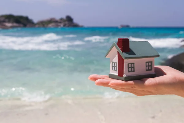 Toy houses keeps on hand against the blue sea. — Stock Photo, Image