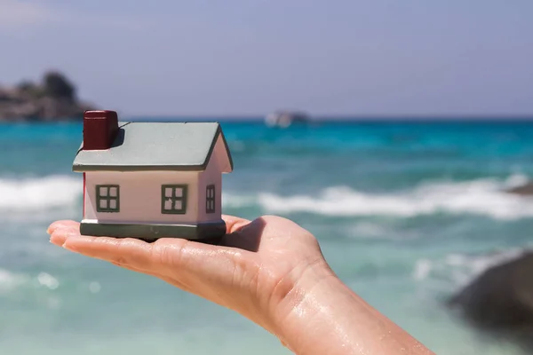 Toy houses keeps on hand against the blue sea. — Stock Photo, Image