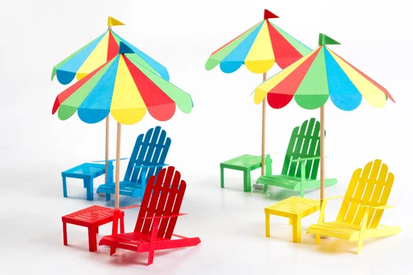 Bright umbrellas folding chairs are made of paper on a white background — Stock Photo, Image