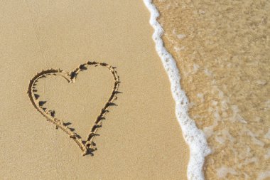 Metniniz için yer ile sabah plaj kum deniz dalgası ile çizilmiş kalp. Yaz tatil kavramı. Romantik aşk arka plan. Sevgililer Günü teması. Üstten Görünüm. Kopya alanı.