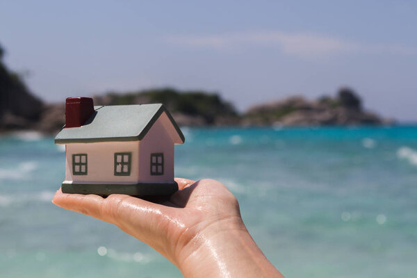 Дом-игрушка на фоне морских волн. Песчаный пляж
.