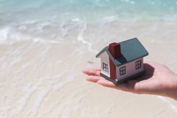 A toy house on a background of sea waves. Sandy beach. — Stock Photo, Image