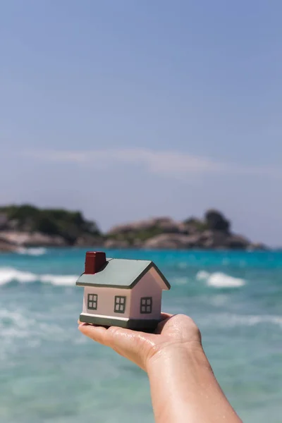 A toy house on a background of sea waves. Sandy beach. — Stock Photo, Image