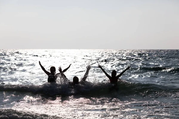 人々のシルエットは 水から飛び降りる 幸せな人たち — ストック写真
