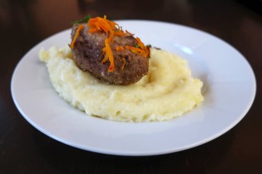 Pirzola, patates püresi ve rendelenmiş havuç.