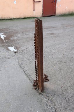 Otoparkın girişini korumak için asfalta zincirli paslı demir parmaklık.