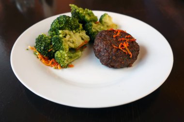 Brokolili et pirzolası ve tabakta havuç.