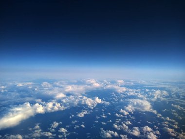 Uçak penceresi görünümü: yüzen bulutlu mavi gökyüzü