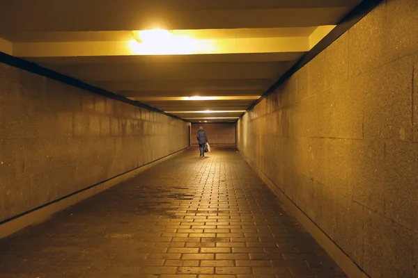 一个女人走在一个铺有花岗岩石板的地下人行横道上 — 图库照片