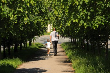 Bir adam ve küçük bir çocuk güneşli bir günde sokakta koşuyorlar.