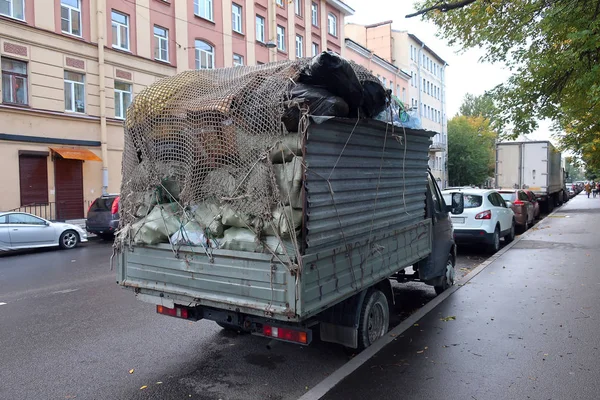 a truck parked on the street loaded with garbage fixed in the back of the truck