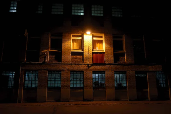 古いレンガ造りの建物の壁を照らす2つの窓の間の提灯 — ストック写真
