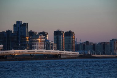 modern şehir binaları ve deniz kenarındaki otoban batan güneşin ışığında.