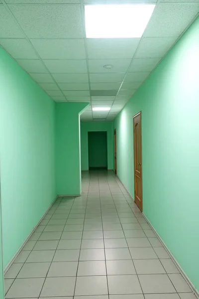 Hospital corridor with false ceiling, green walls and tiled floor