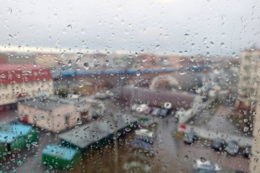 Şehir manzarasına karşı pencere camında yağmur üstüne yağmur damlaları