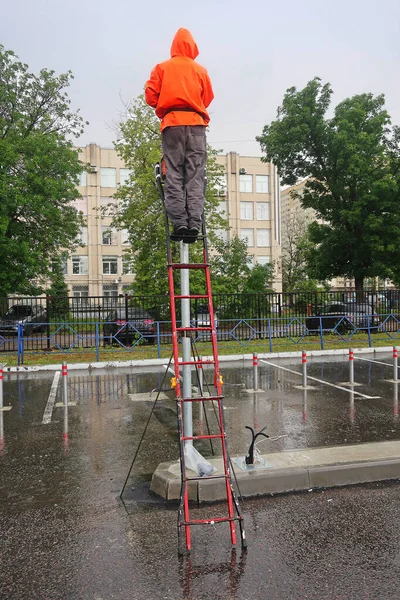 Hombre Con Una Chaqueta Naranja Con Una Capucha Una Escalera —  Fotos de Stock