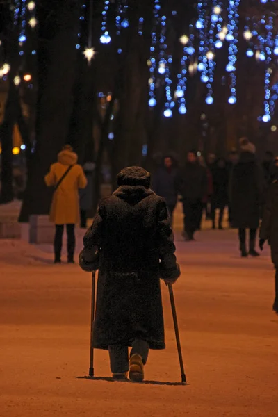 Starší Žena Opírající Dvě Tyčinky Prochází Zimním Parkem Zdobeným Věnci — Stock fotografie